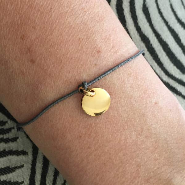 Cord bracelet with small round gold-plated medal